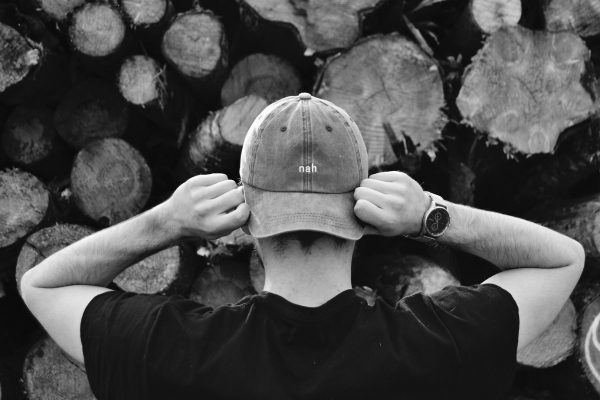 boy in black t shirt holding his hat from both hand from back shows off custom patch